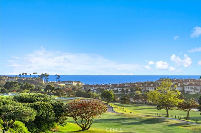 surrounding community featuring a water view, fence, and a lawn