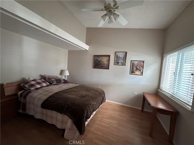 bedroom with a textured ceiling, wood finished floors, ceiling fan, and baseboards