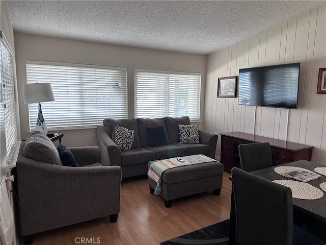 living room with wood walls, a textured ceiling, and wood finished floors