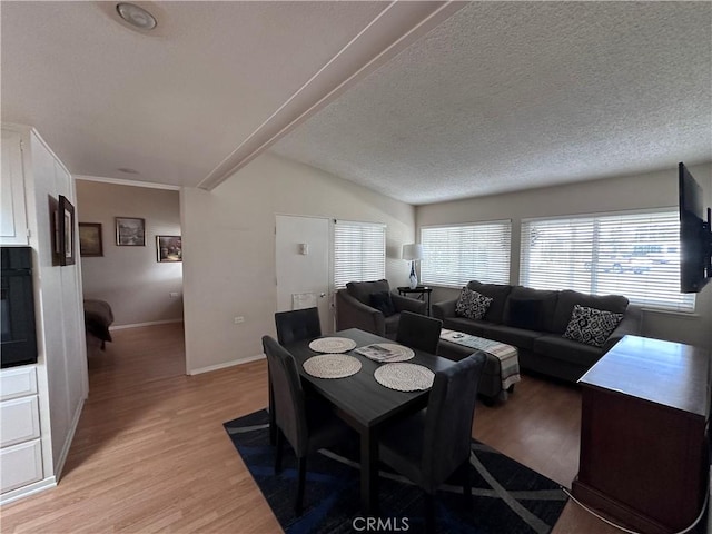 dining area with light wood-style floors, baseboards, and a textured ceiling