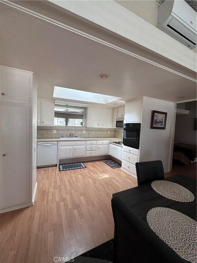 kitchen featuring oven, dishwasher, a sink, light wood-type flooring, and stainless steel microwave