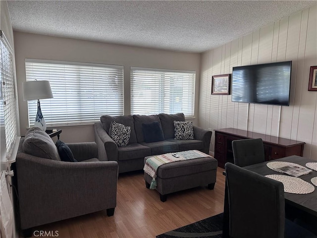 living room featuring wooden walls, wood finished floors, and a textured ceiling