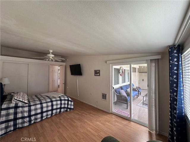 bedroom with a closet, baseboards, a textured ceiling, light wood finished floors, and access to exterior