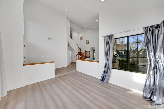 unfurnished living room with stairs, visible vents, wood finished floors, and recessed lighting