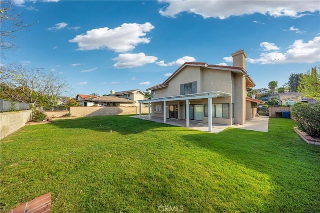 rear view of house featuring a fenced backyard, a patio, a chimney, and a lawn