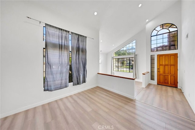 foyer entrance featuring baseboards, recessed lighting, high vaulted ceiling, and wood finished floors