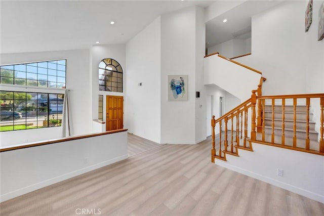 interior space with recessed lighting, baseboards, high vaulted ceiling, wood finished floors, and stairway