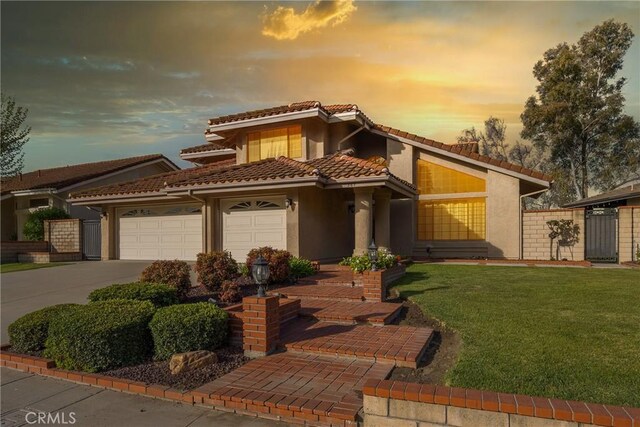 view of front of property featuring a lawn, driveway, a tiled roof, an attached garage, and stucco siding
