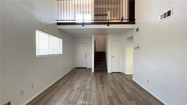 20211 Carlisle Rd, Apple Valley, CA 92307 - unfurnished living room with baseboards, stairway, healthy amount of natural light, wood finished floors, and a towering ceiling