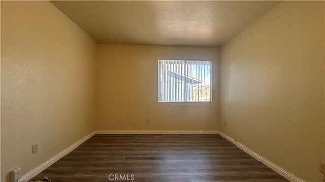 20211 Carlisle Rd, Apple Valley, CA 92307 - empty room featuring dark wood-style flooring, baseboards, and a textured ceiling