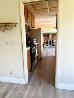kitchen with stainless steel microwave, wood finished floors, baseboards, and black gas stove