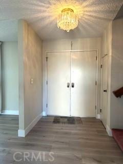 interior space featuring baseboards, wood finished floors, and a notable chandelier