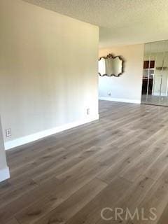 unfurnished room featuring wood finished floors, baseboards, and a textured ceiling