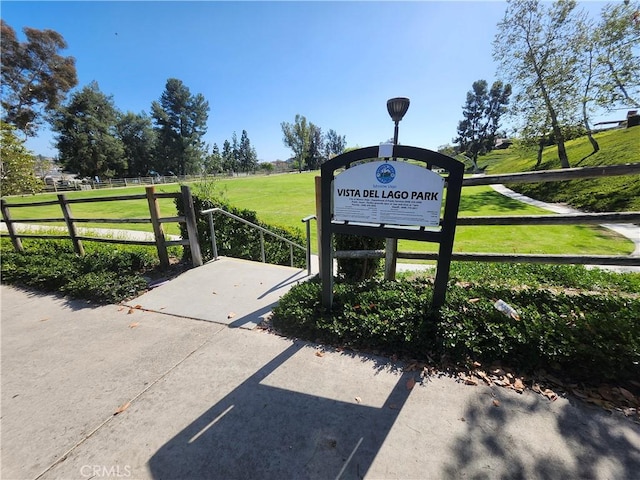 view of property's community featuring fence, a lawn, and a rural view