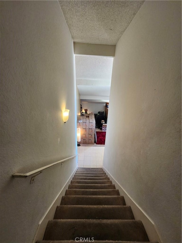 stairway with a textured wall and a textured ceiling