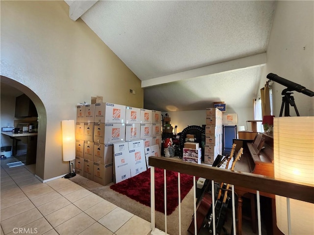 corridor with tile patterned floors, arched walkways, vaulted ceiling, and a textured ceiling
