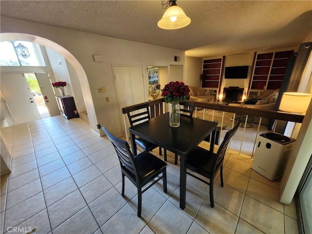 dining space featuring visible vents, arched walkways, tile patterned flooring, and a textured ceiling