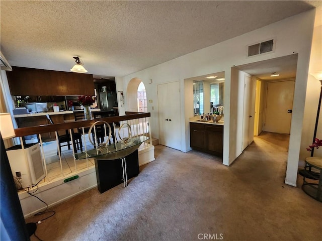 interior space with visible vents, arched walkways, carpet flooring, and a textured ceiling
