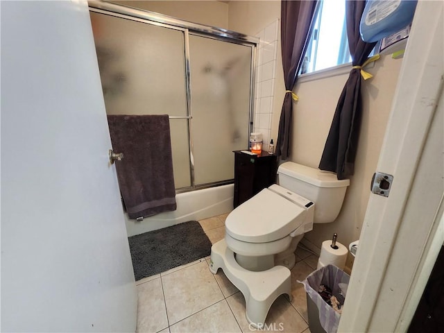 bathroom with tile patterned flooring, toilet, and bath / shower combo with glass door