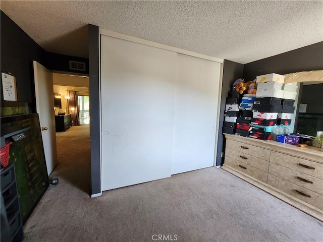 bedroom featuring a closet, visible vents, a textured ceiling, and carpet floors