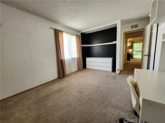 unfurnished bedroom with visible vents, a textured ceiling, baseboards, and carpet floors