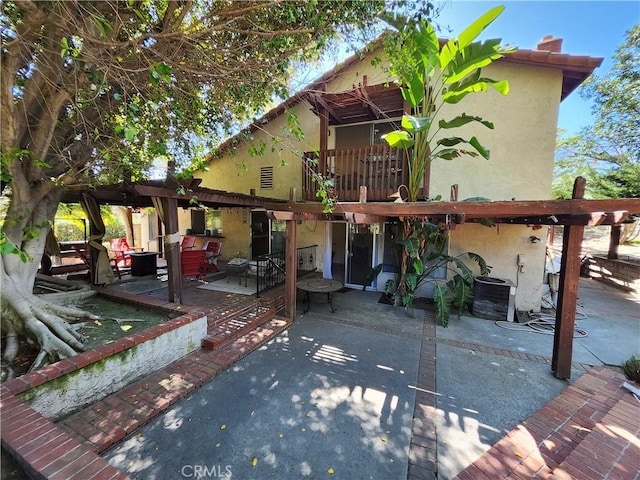 rear view of house with a patio and stucco siding