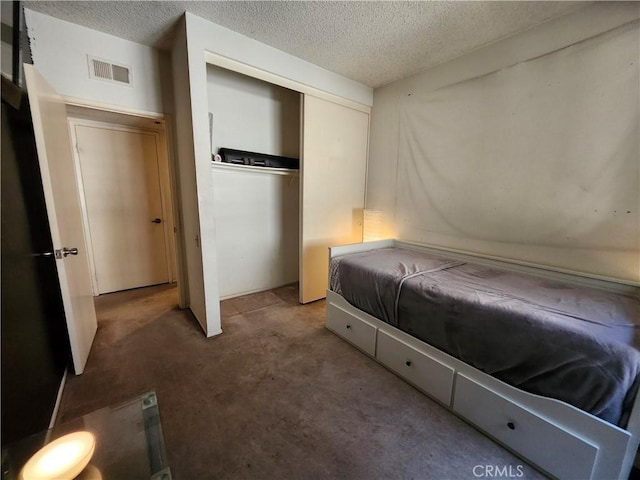 bedroom featuring a closet, carpet flooring, visible vents, and a textured ceiling