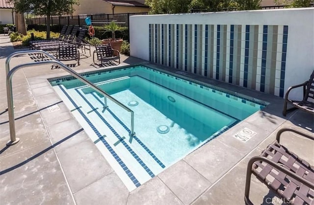 view of pool with fence, a hot tub, and a patio area
