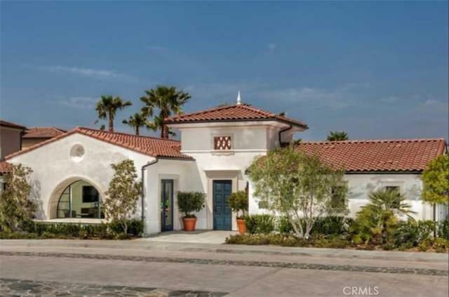 mediterranean / spanish house with a tiled roof and stucco siding