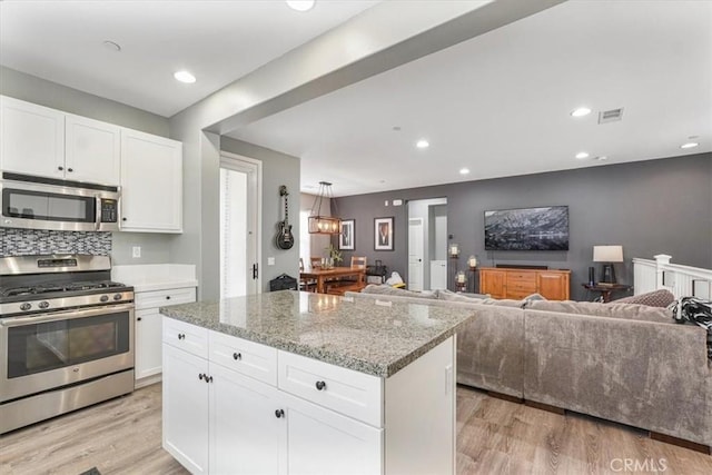 kitchen with white cabinets, stainless steel appliances, visible vents, and light wood-type flooring