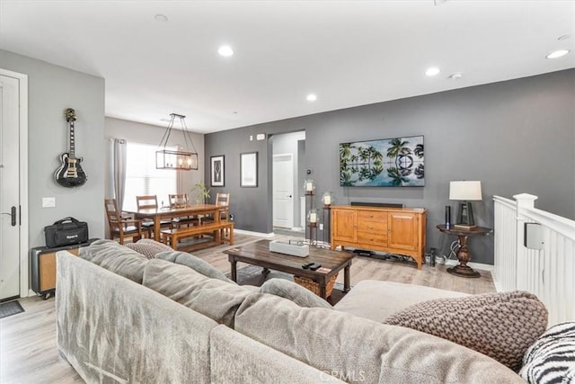 living room featuring recessed lighting, baseboards, an inviting chandelier, and light wood-style floors