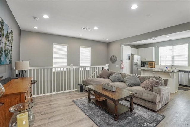 living room featuring a wealth of natural light, light wood finished floors, and visible vents