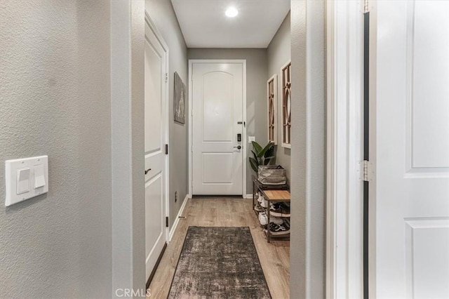 doorway with baseboards and light wood-style floors