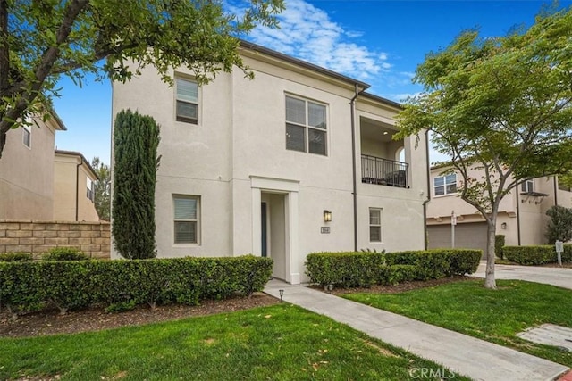 townhome / multi-family property featuring driveway, a front yard, and stucco siding