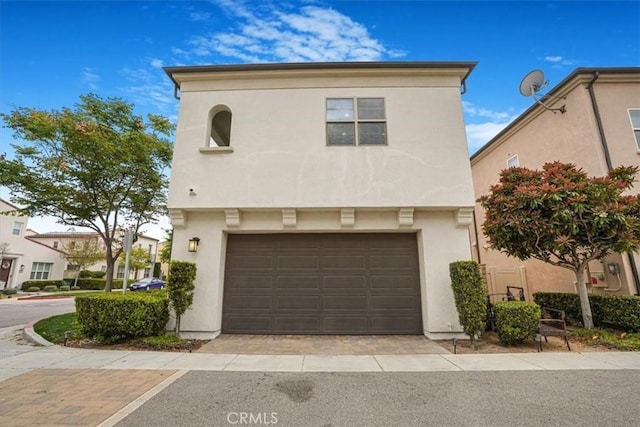 front facade featuring stucco siding, driveway, and a garage