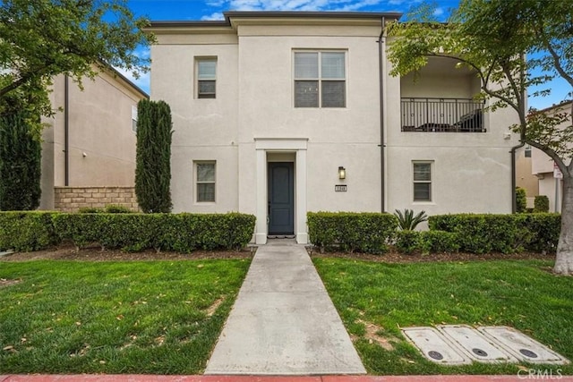 view of front of house with stucco siding and a front lawn