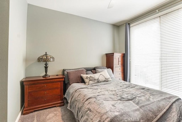 bedroom featuring baseboards, carpet flooring, ceiling fan, and multiple windows