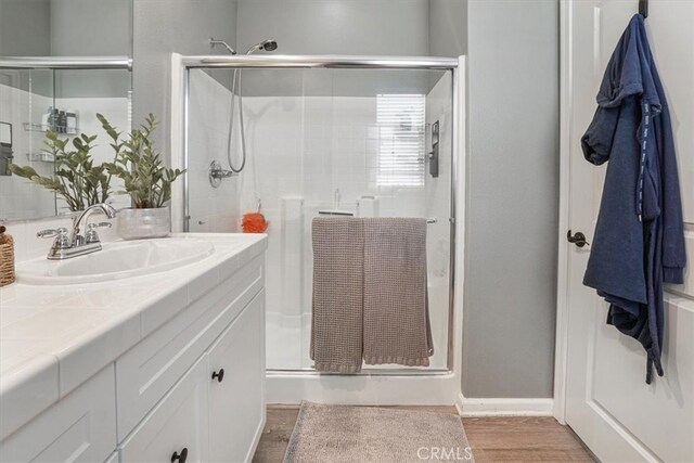 bathroom featuring wood finished floors, vanity, and a stall shower