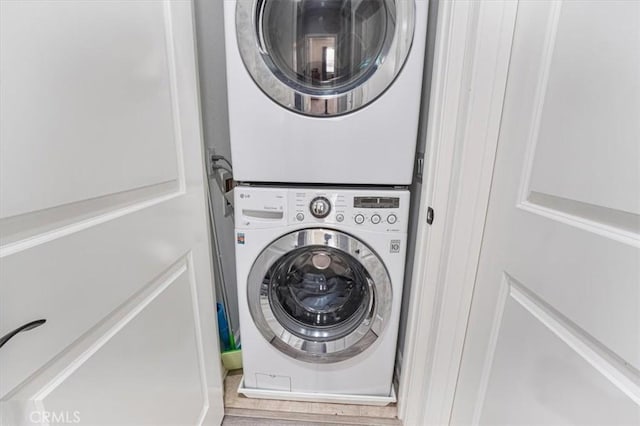 laundry room featuring wood finished floors, stacked washer / dryer, and laundry area