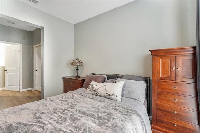 bedroom with baseboards, wood finished floors, and visible vents