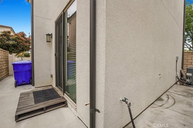 entrance to property featuring a patio area, stucco siding, and fence