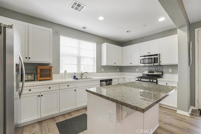 kitchen with a center island, stainless steel appliances, visible vents, and light wood-style floors