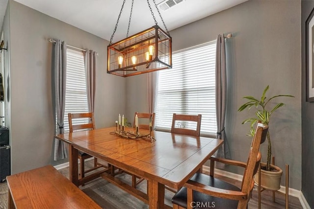 dining area with baseboards, a notable chandelier, wood finished floors, and visible vents