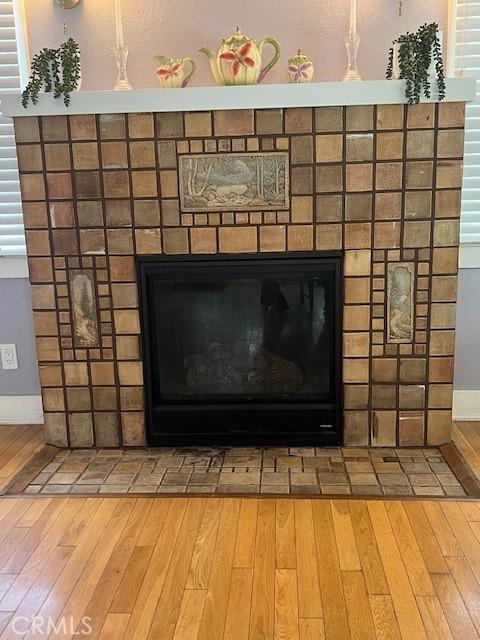 interior details featuring a fireplace with flush hearth, wood finished floors, and baseboards