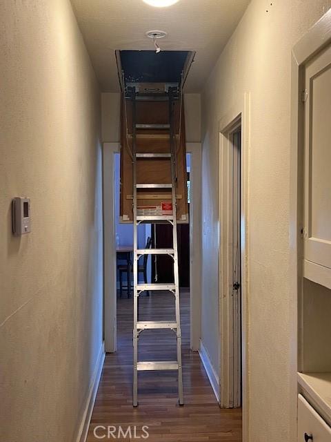 hall featuring dark wood-style flooring and baseboards