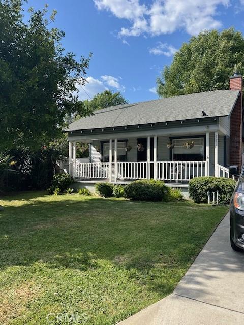 view of front of property with a chimney, covered porch, and a front lawn