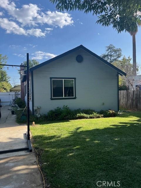 view of side of home featuring fence, a patio, and a lawn