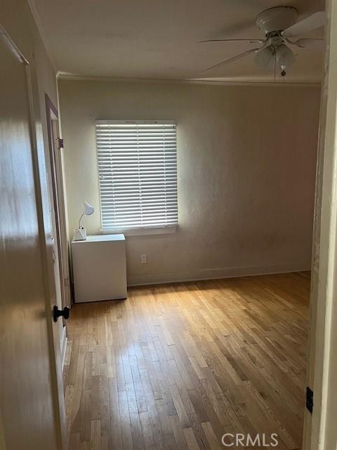 unfurnished room with ornamental molding, baseboards, a ceiling fan, and hardwood / wood-style floors