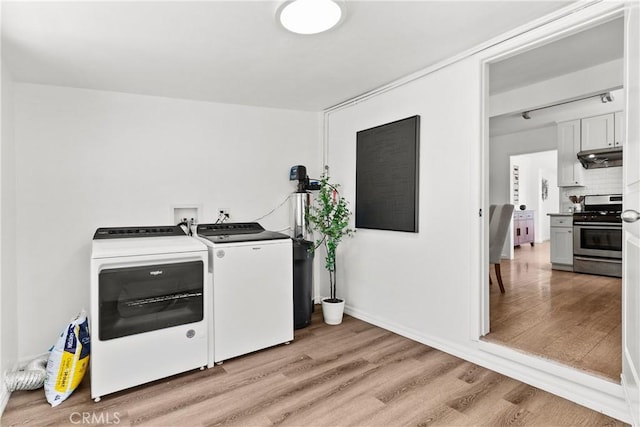 washroom featuring baseboards, light wood-type flooring, laundry area, and washing machine and clothes dryer