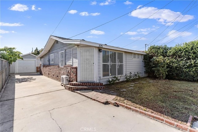 view of home's exterior featuring an outdoor structure, driveway, brick siding, a garage, and fence